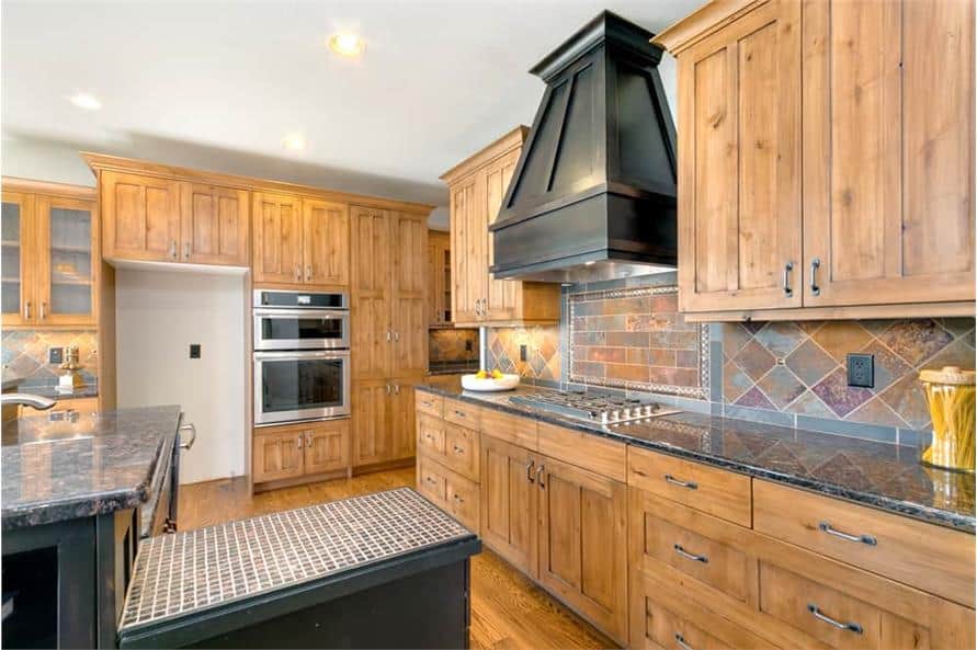 Kitchen with natural wood cabinetry, granite countertops, and a built-in cooktop.