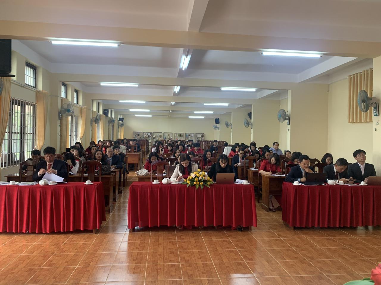 A group of people sitting at tables in a room with red tablecloths

Description automatically generated