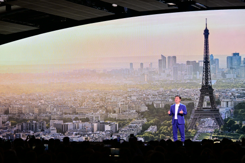 A person standing in front of a large screen with a large tower in the background

Description automatically generated