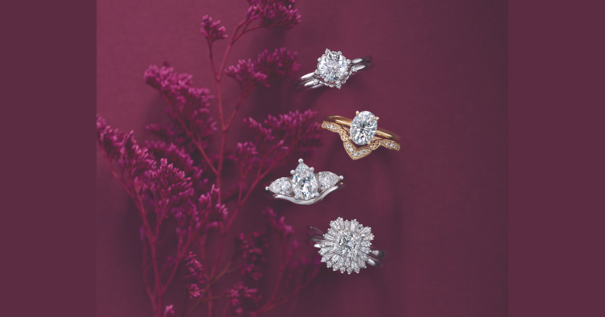 Four beautiful engagement rings in various settings with a burgandy background