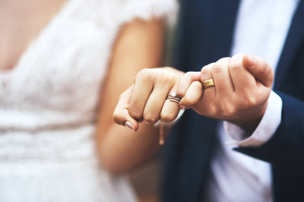 Close-up of a bride and groom holding hands

Description automatically generated