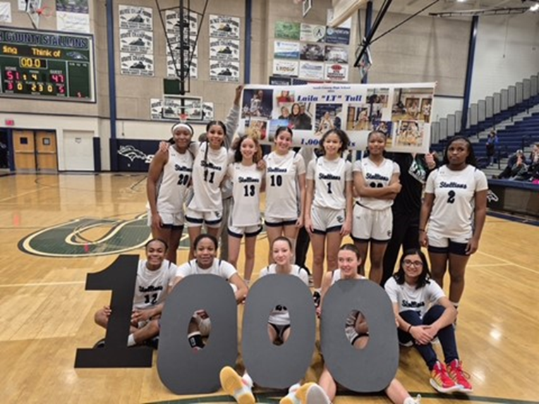 South County High School girls basketball team holding a 1,000 point sign. 