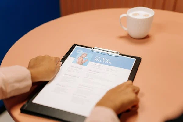 Close-up of businesswoman's hand holding resume in hand with coffee cup on table