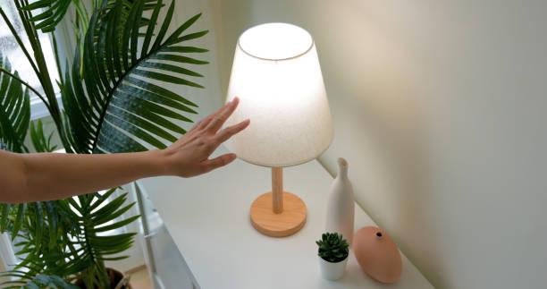 turn on lamp by touching woman is turning on lamp by touching with sense light at home BUYnBLUE lamps: stylish and functional lighting for every home stock pictures, royalty-free photos & images