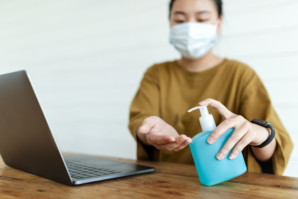 A woman is working at office and using sanitizer to make sure her hands are germs free