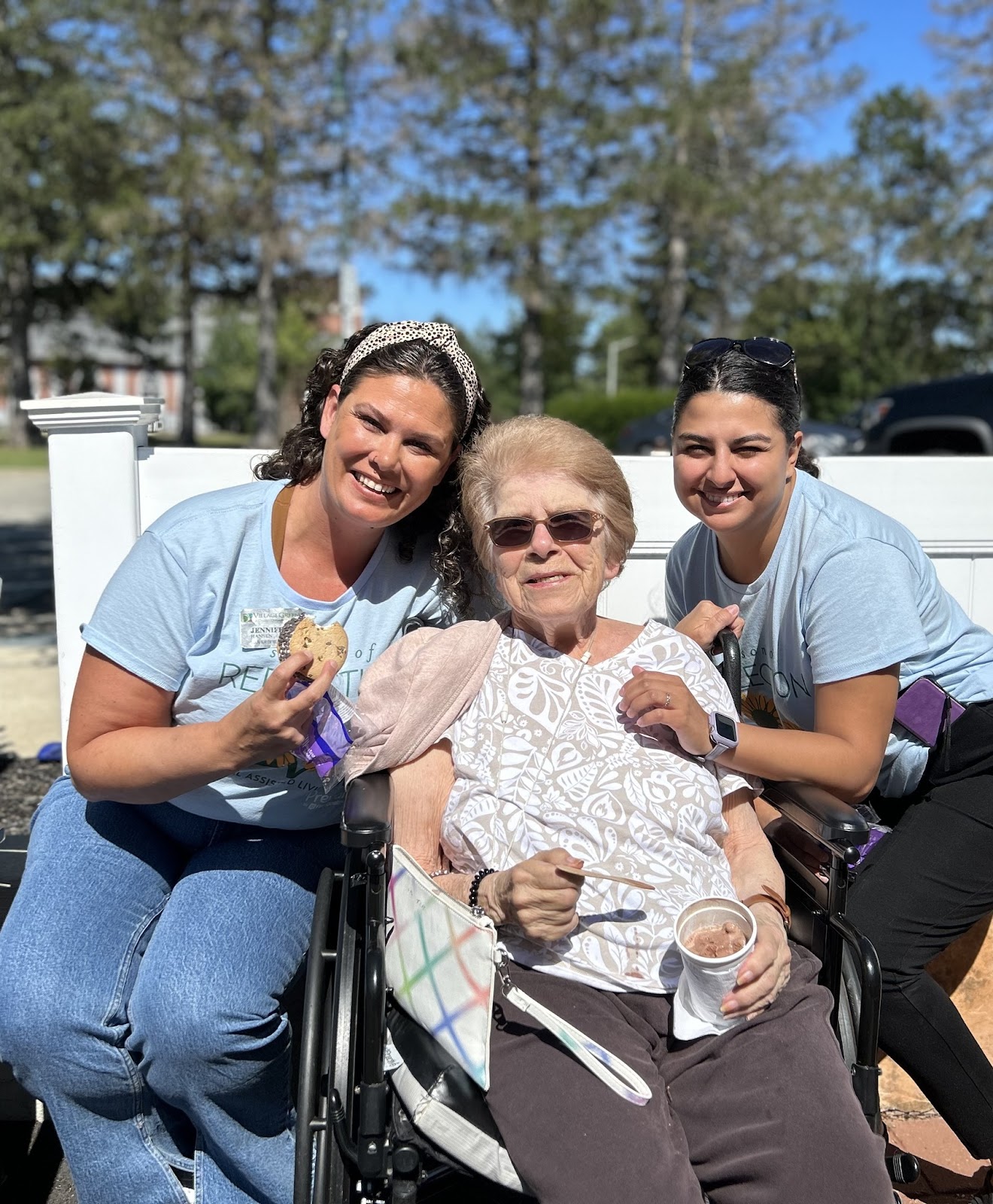 A woman in a wheel chair with hot chocolate while two women sit next to her and smile