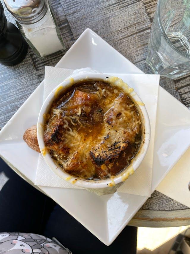 A bowl of soup on a plate

Description automatically generated