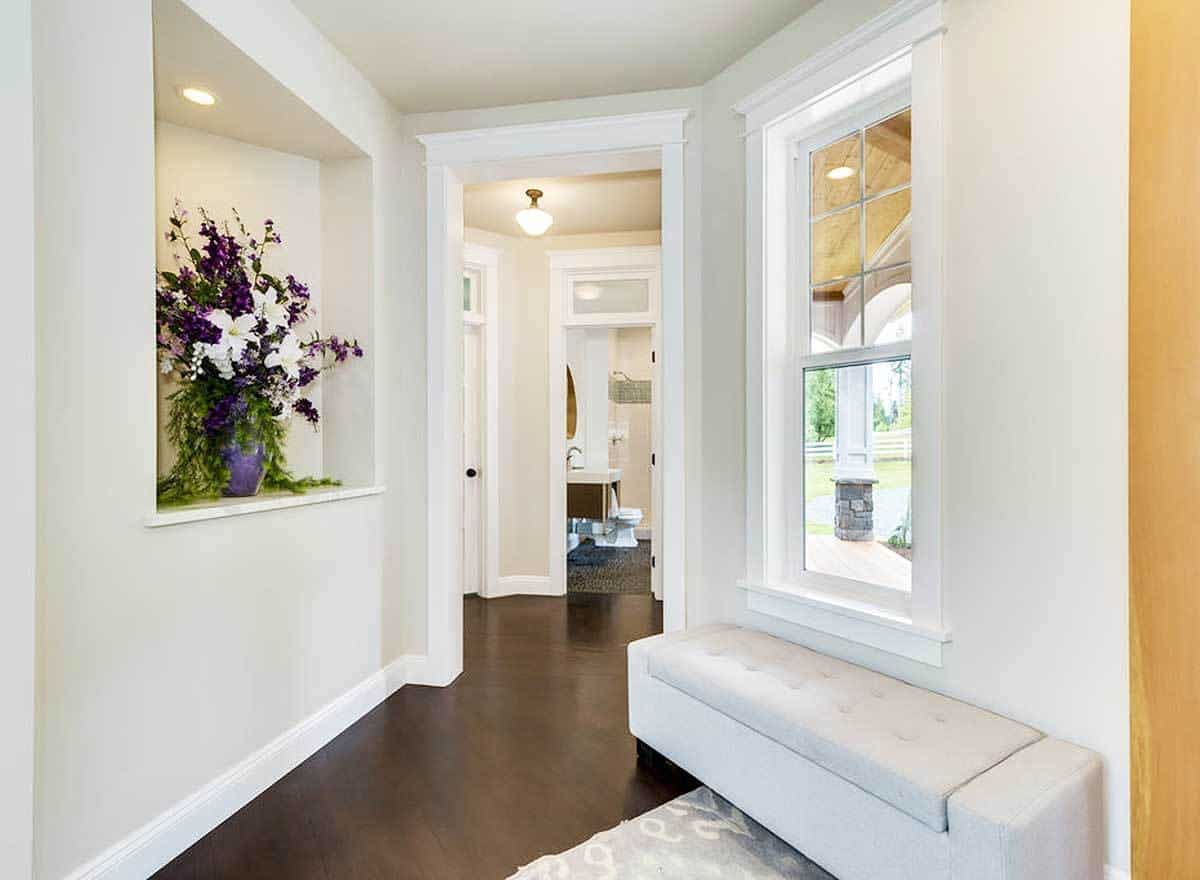 The foyer includes a tufted bench and a niche wall filled with a beautiful flower vase.