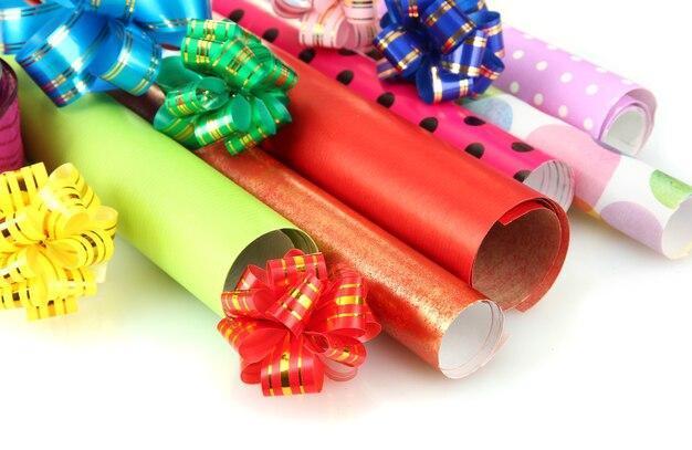 Rolls of Christmas wrapping paper with ribbons isolated on white surface