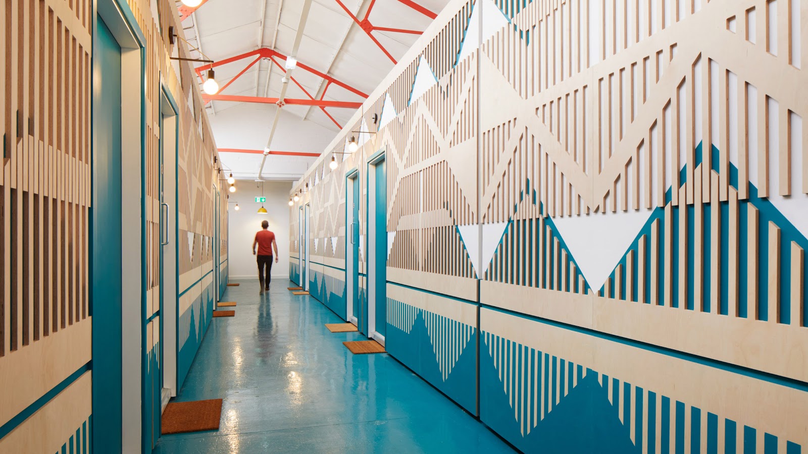 A person walks down a corridor with vibrant blue and white geometric patterns on the walls—a stunning testament to industrial adaptive reuse.