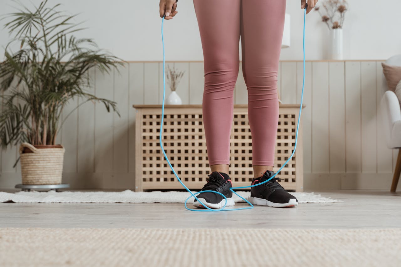 picioarele unei femei imbracate sport care sare coarda in apartament
