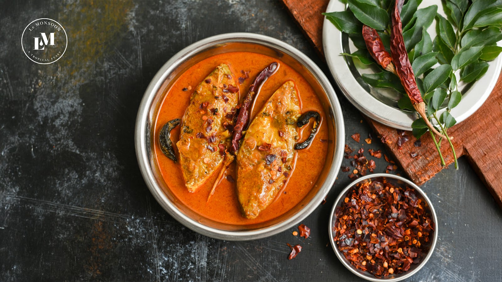 A vibrant silver bowl filled with spicy fish masala curry.