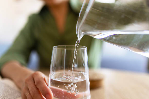 A person pouring water into a glass, highlighting the role of hydration in maintaining magnesium balance and overall brain health.