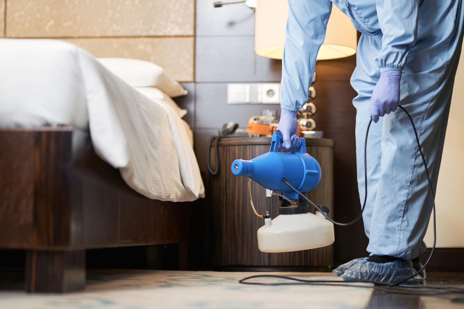 Close-up of a pest control professional treating a bedroom for bed bugs.