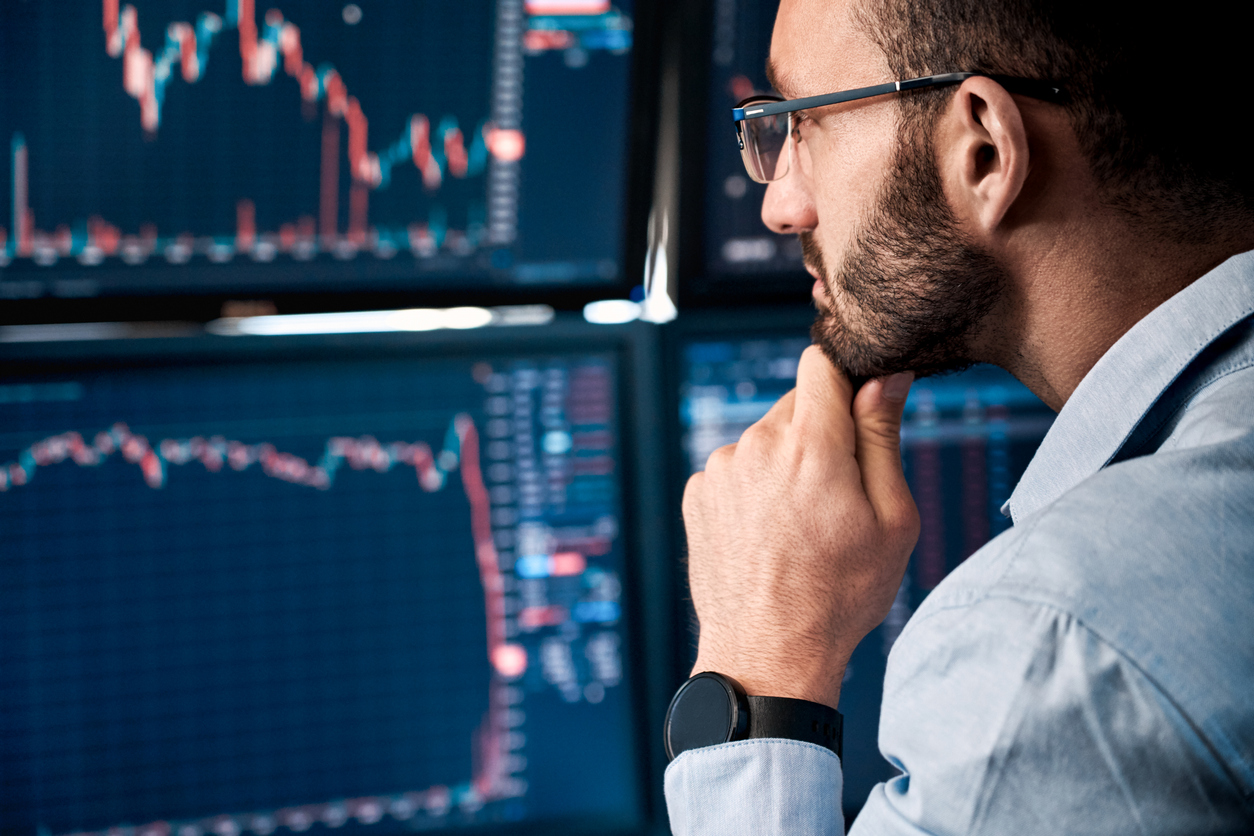 Homem olhando para os gráficos de trade nas telas