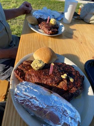 A plate of meat with a potato and a baked potato on a table Description automatically generated