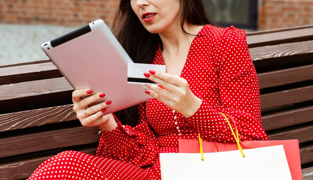 A person holding a credit card and a tabletDescription automatically generated