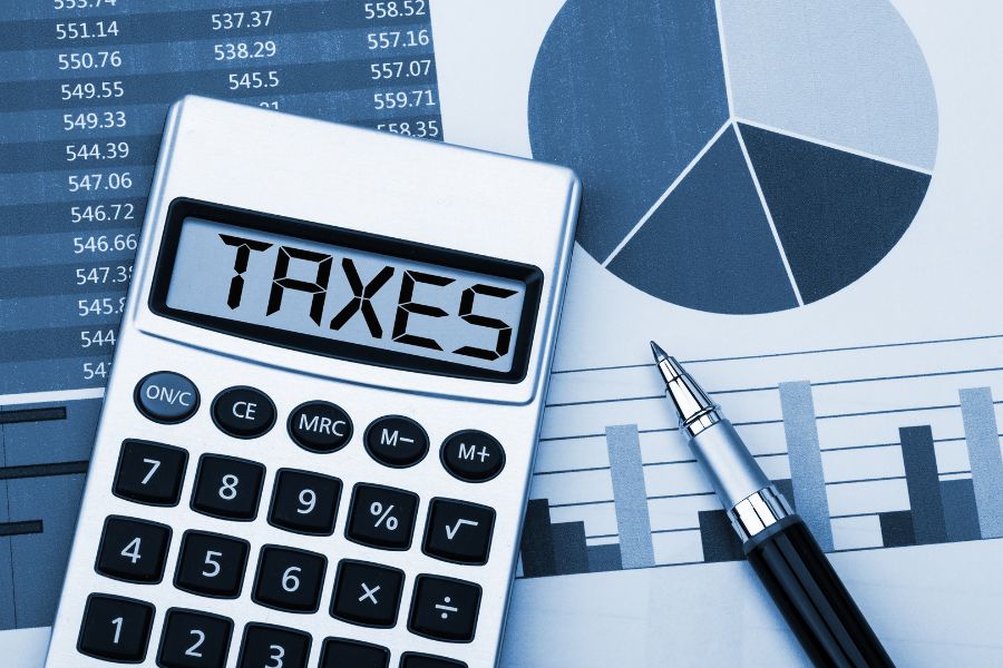 Calculator showing 'TAXES' with charts and pen for financial planning