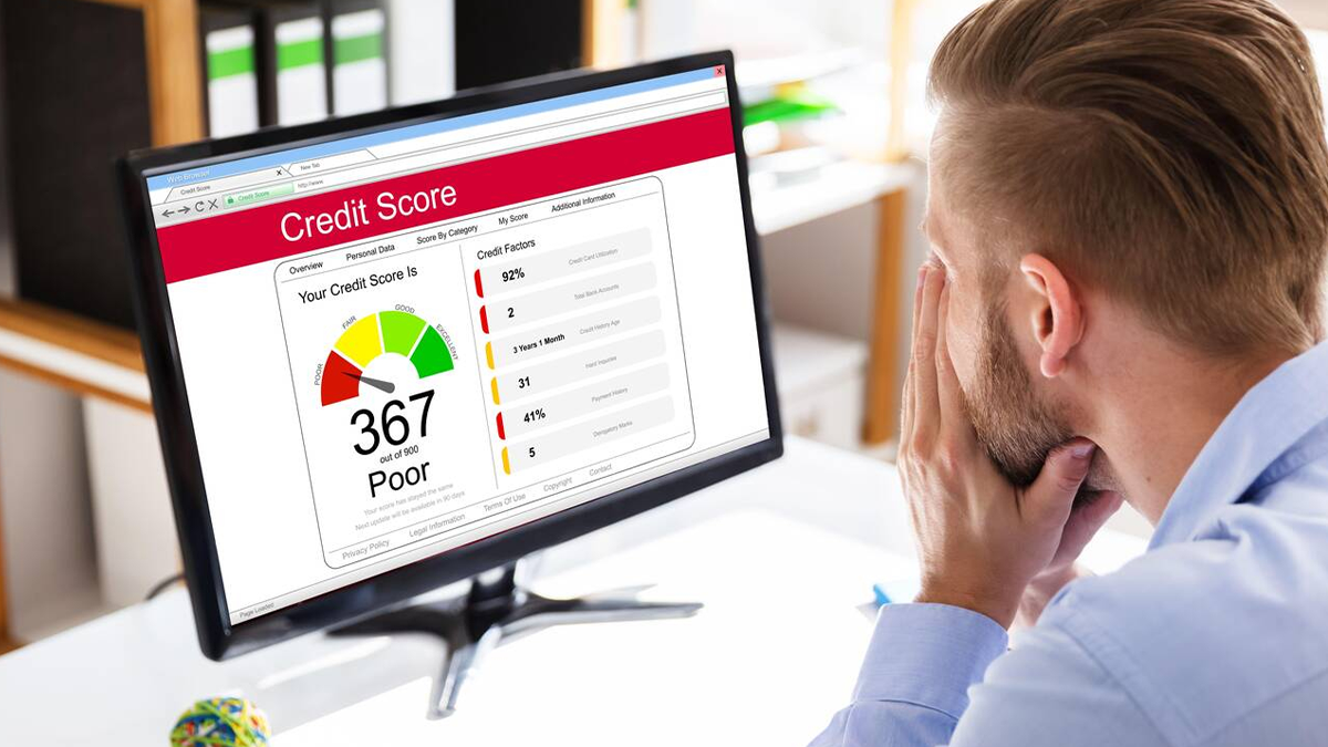 Man worriedly looking at his poor credit score of 367 from his computer screen