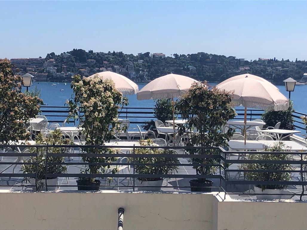 A group of tables and chairs with umbrellas on a rooftop

Description automatically generated