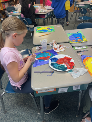 student paints while seated at a desk