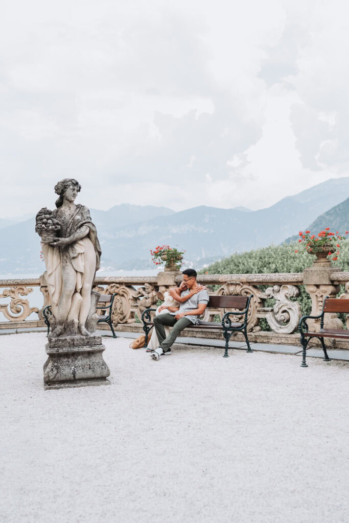 couple sit on bench and cuddle during their lake como engagement session.