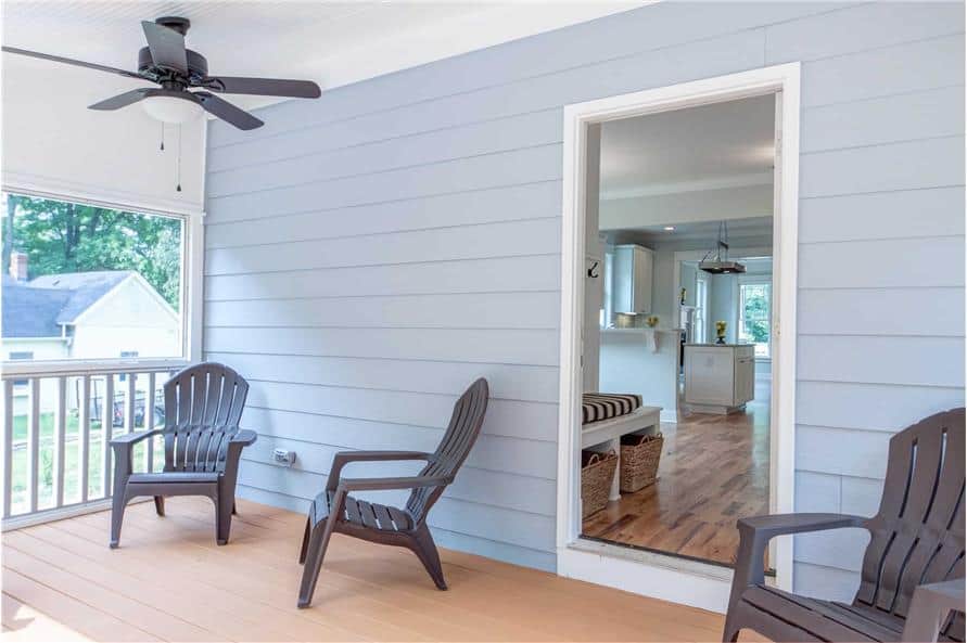 The screened porch includes a ceiling fan and wooden lounge chairs over wide plank flooring.