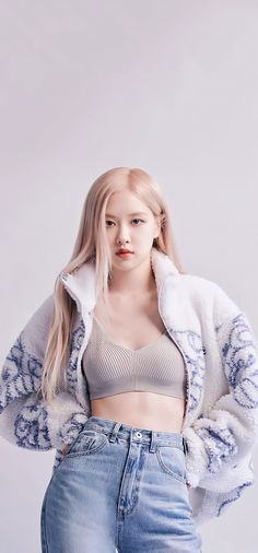 This contains an image of Rosé with long blonde hair wearing jeans and a crop top, standing in front of a white background