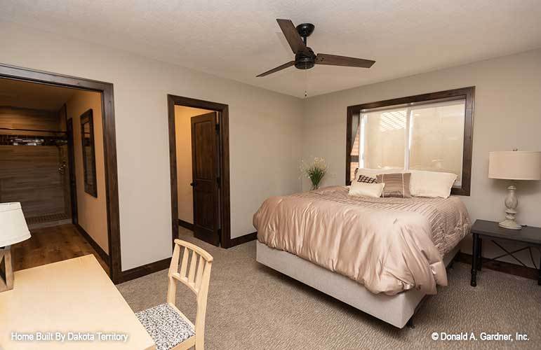 Another bedroom with beige walls, a platform bed, and a wooden desk paired with a matching chair.