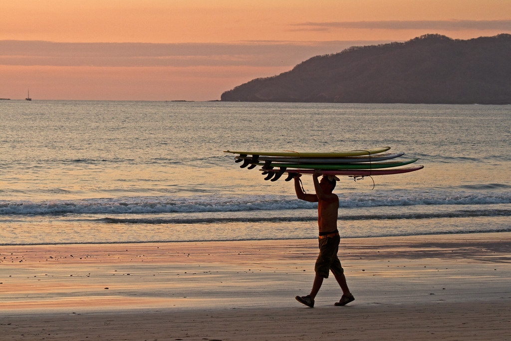 Clear water as its sunset time sky turns into yellow and orange color and man carrying object on his head