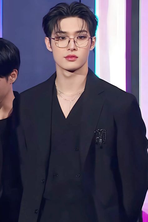 This contains an image of ATEEZ Mingi's in a black suit and glasses is standing next to another male with dark hair