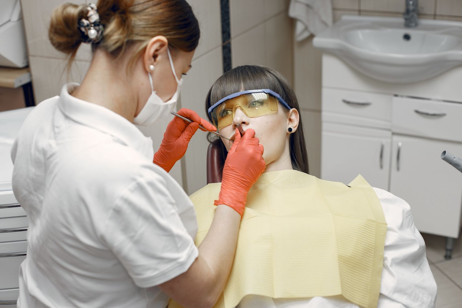 Female dentist examining a young woman’s teeth during a dental emergency visit in a clinic.