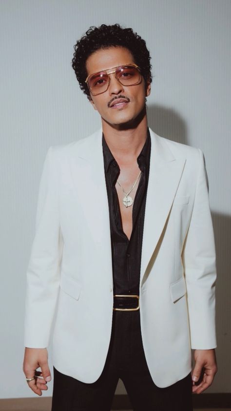 This contain an image of Bruno Mars in a white jacket and black shirt with sunglasses on posing for the camera