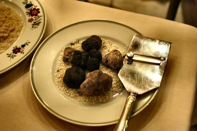 A plate of black truffles and a pizza cutter

Description automatically generated