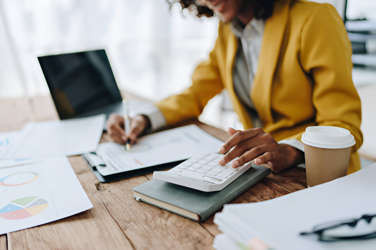 Businesswoman working with financial documents and a calculator, demonstrating the importance of bookkeeping for accurate business management.