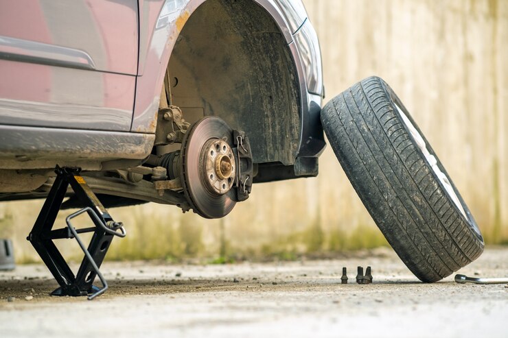 Car raised on a jack with the wheel removed for fender rolling