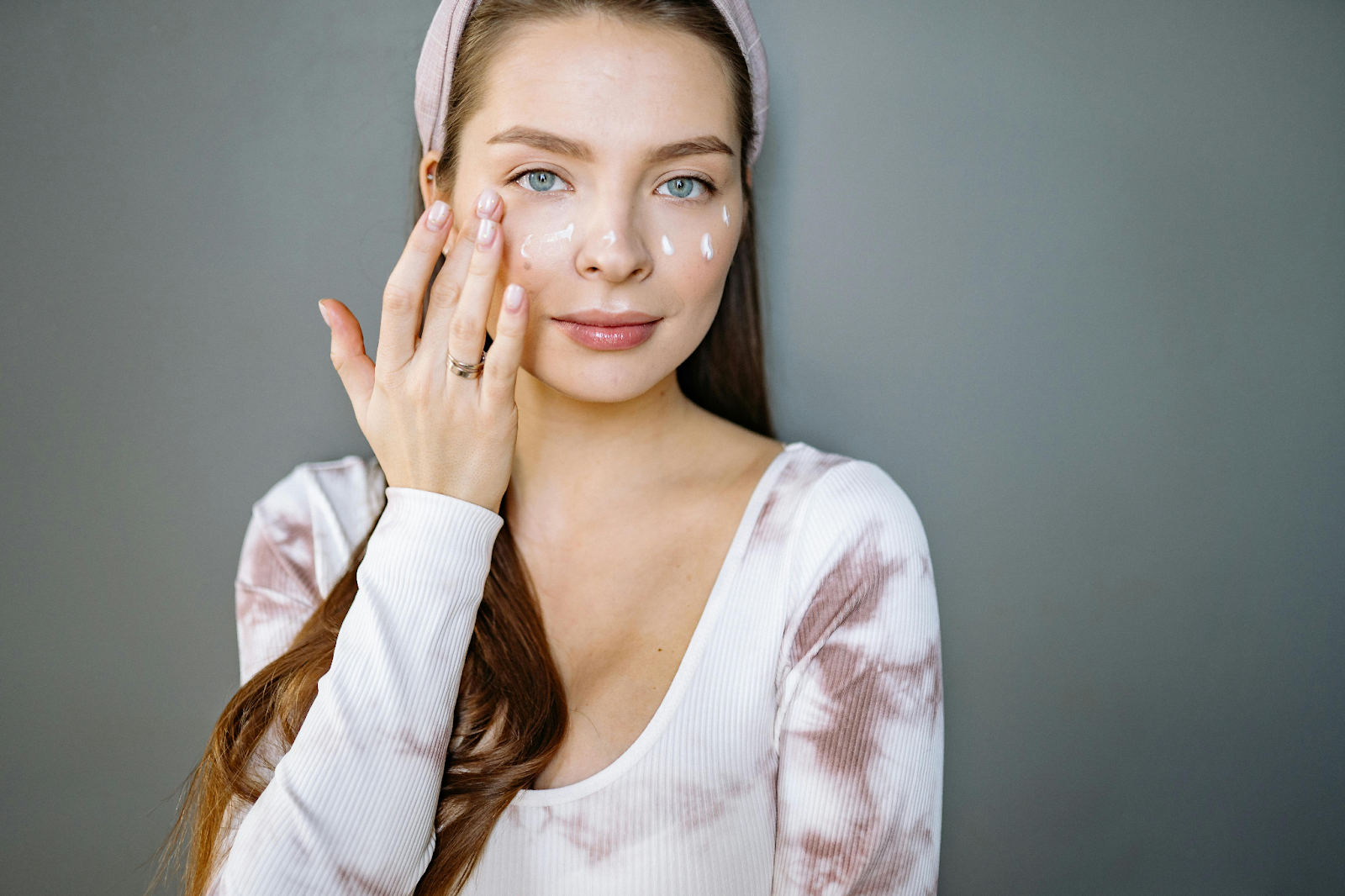 A woman applying moisturizer to her face.