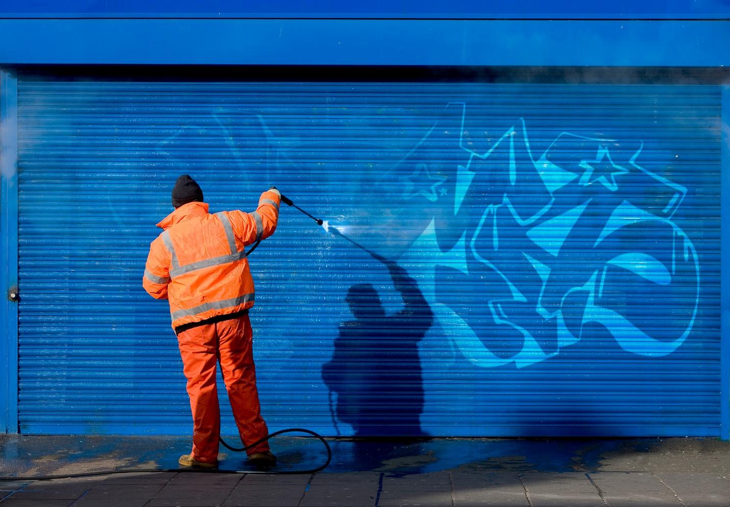 A person spraying graffiti on a wall

Description automatically generated