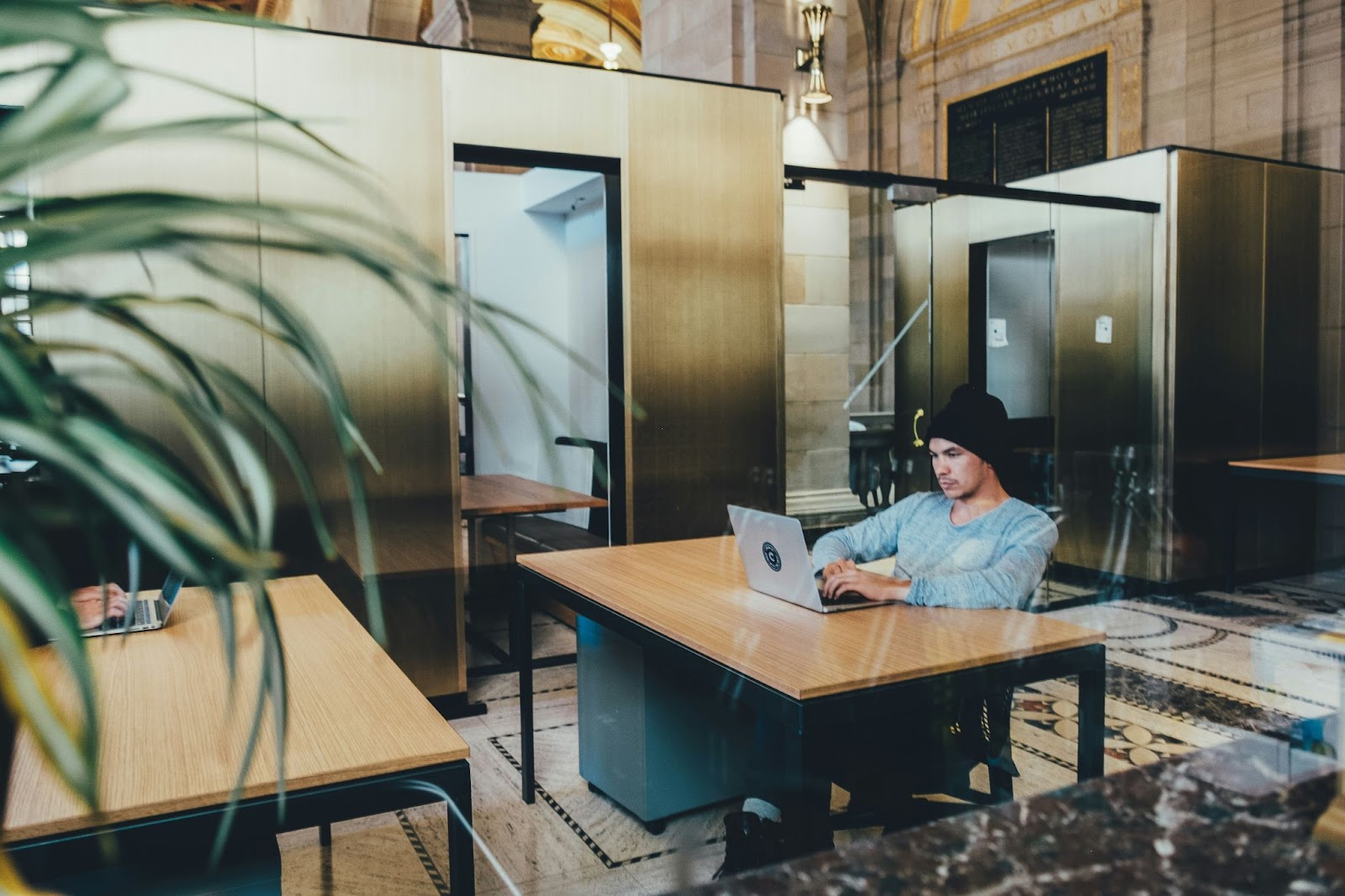 Man in a black hat working on a gray laptop