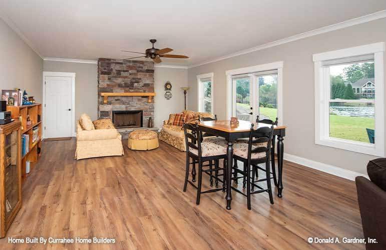 Bonus room with a 4-seater dining set, facing sofas, a skirted ottoman, and a brick fireplace.