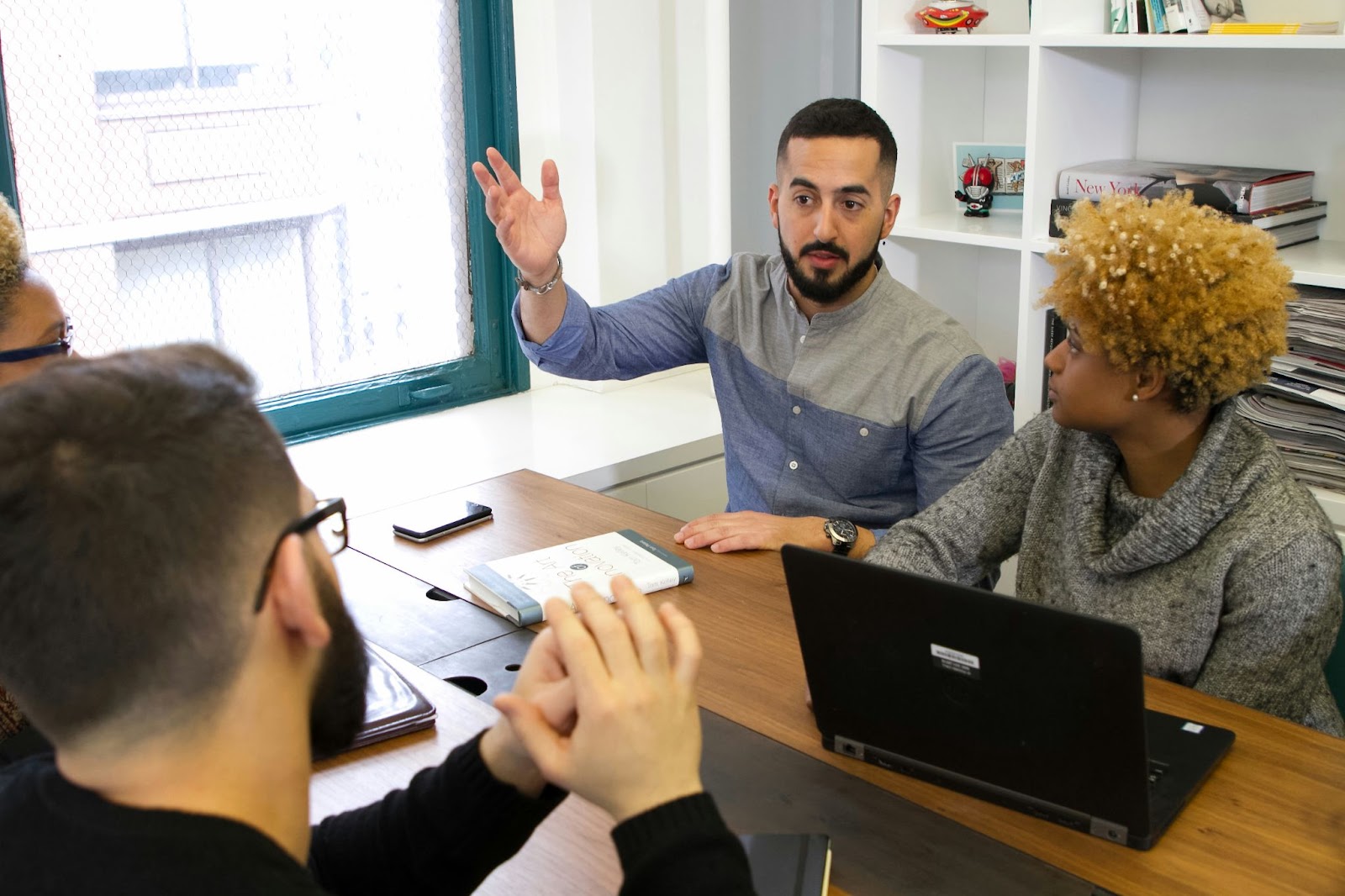 A group of people having a discussion at a table, with one person gesturing while speaking.