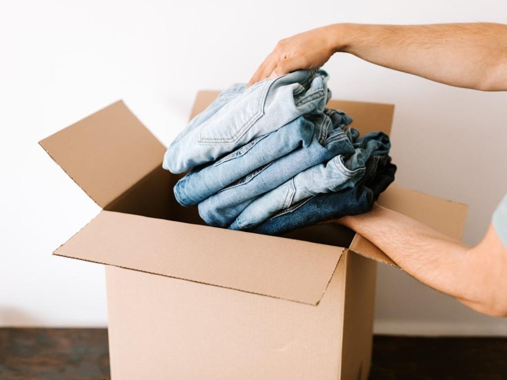  Man packing clothes into carton box.