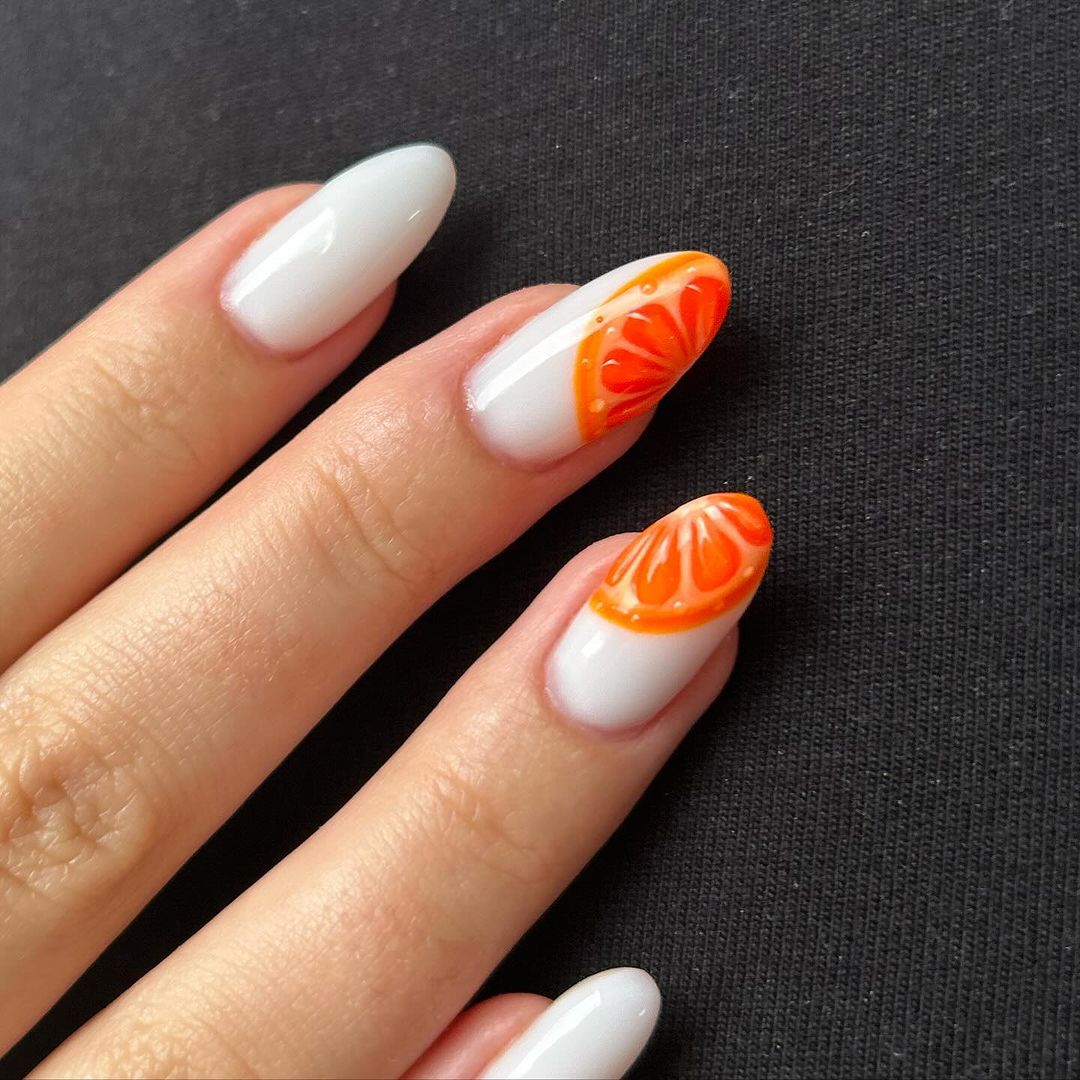 Close up of nails with glittery orange nails having Orange Slice Designs