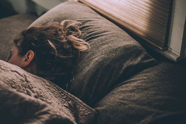 Woman lying on a bed, reflecting and resting, symbolizing self-care and healing