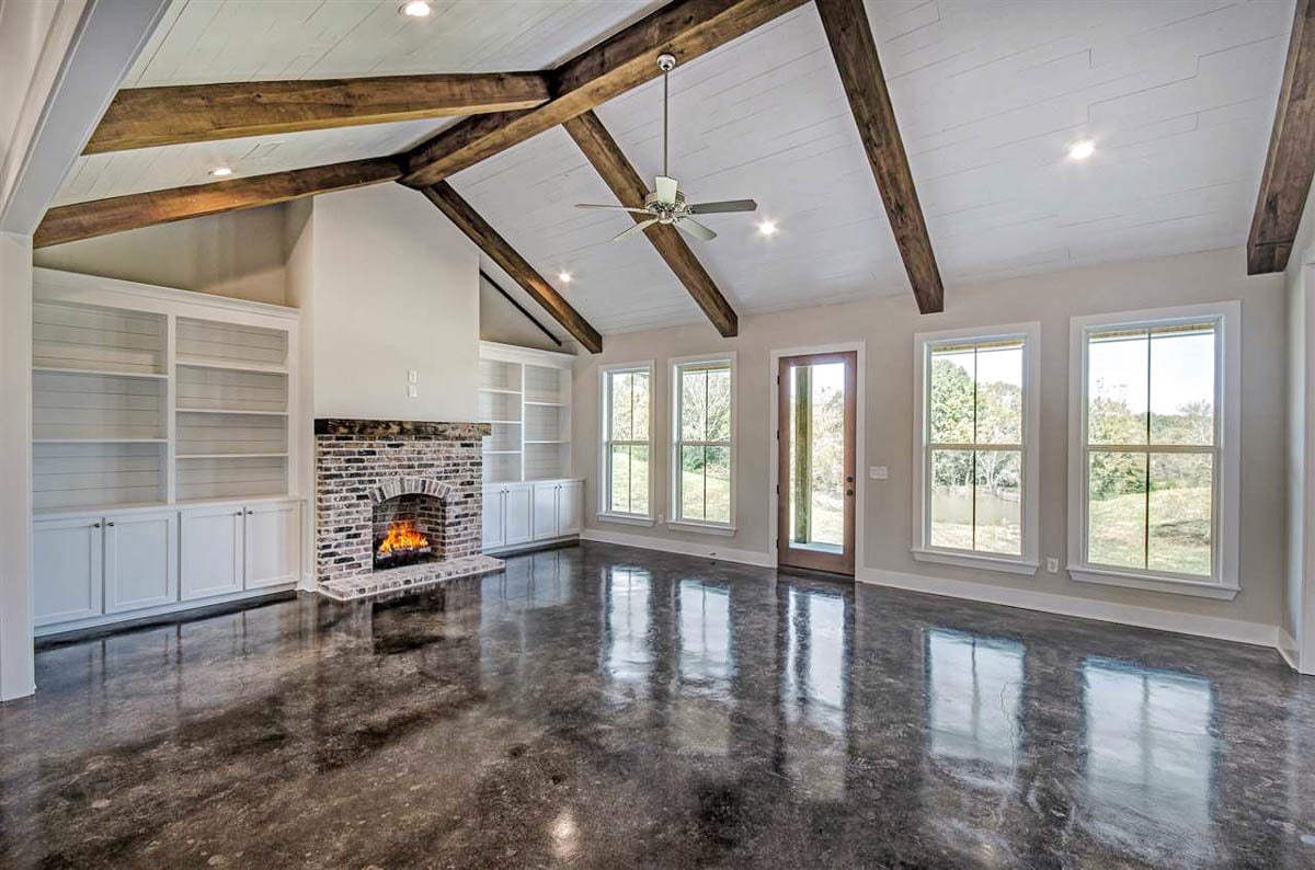 Living room with beamed ceiling, a brick fireplace, and white built-ins.