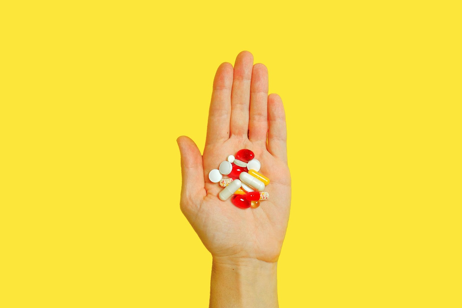 A hand holding different kinds of prescription pills