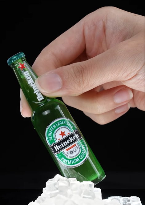 A transparent Heineken 3D printed bottle on a stack of ice.