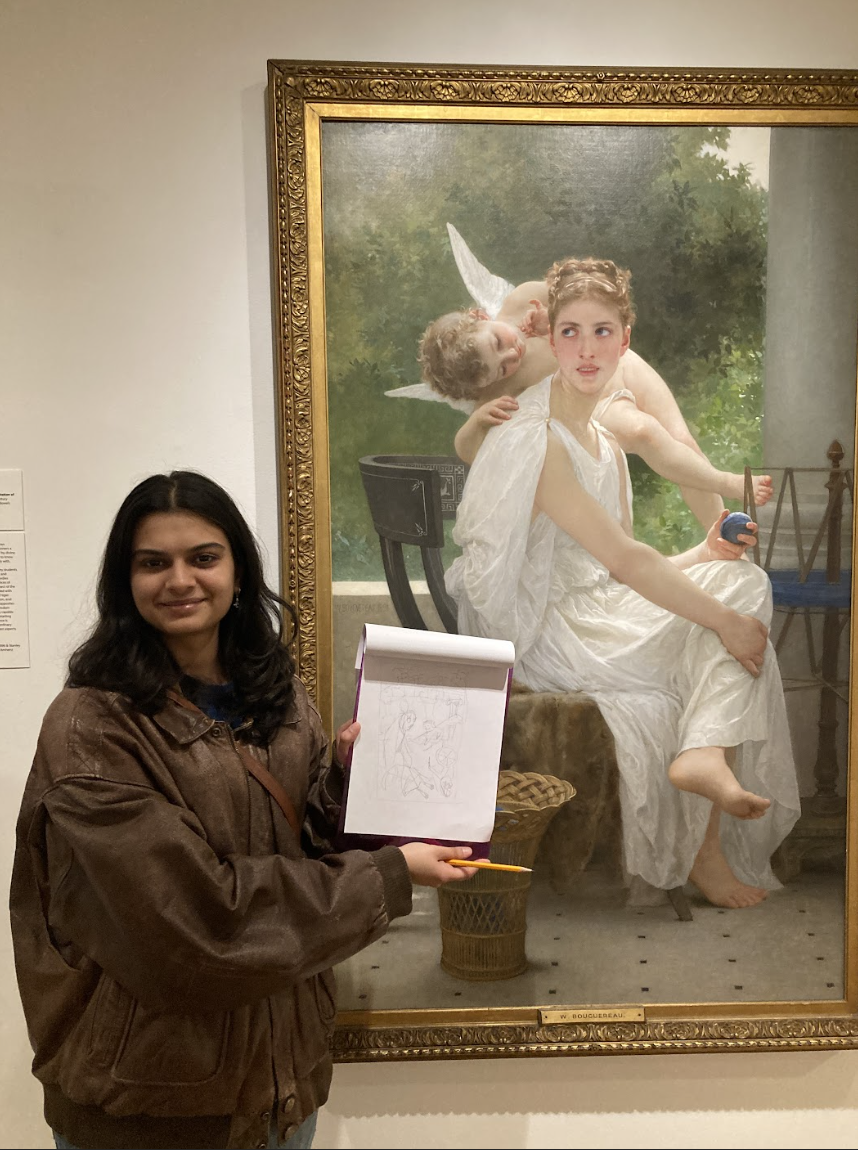 A young person in a brown jacket stands next to a life-size painting of a seated woman, holding a sketchpad with a drawing.