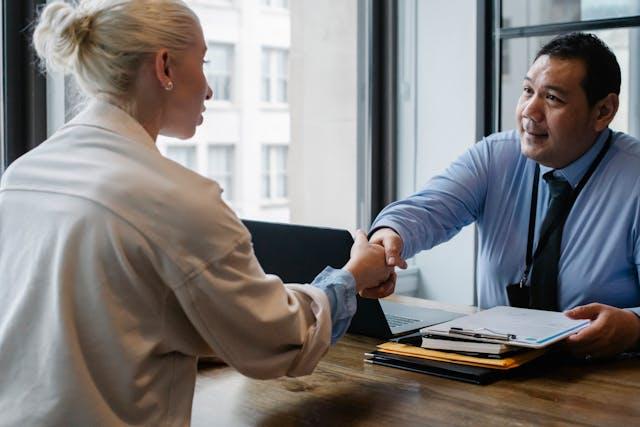 A woman and a man shaking hands in an office