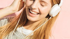 Young Woman Listening Music Headphone Attach Through Mobile Phone Against Pink Background